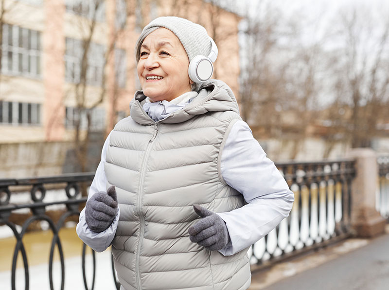 Woman-dressed-for-winter-wearing-headphones-and-jogging-mobile Woman dressed for winter wearing headphones and jogging